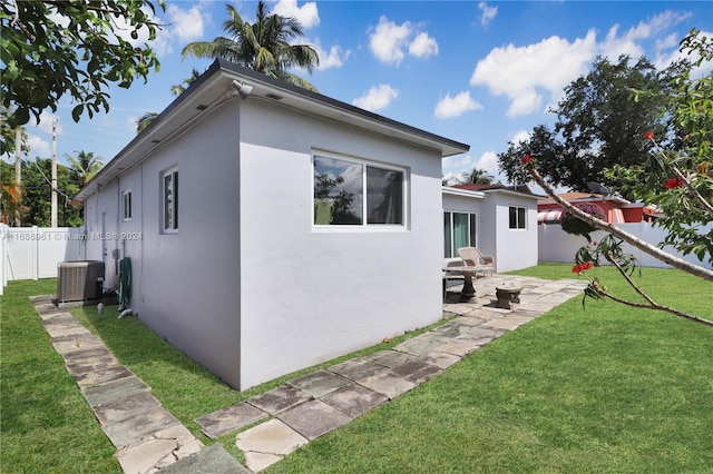 back of property featuring a lawn and central air condition unit