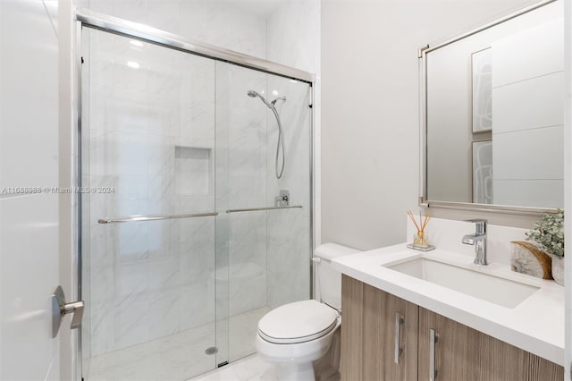 bathroom with toilet, vanity, and a shower with door