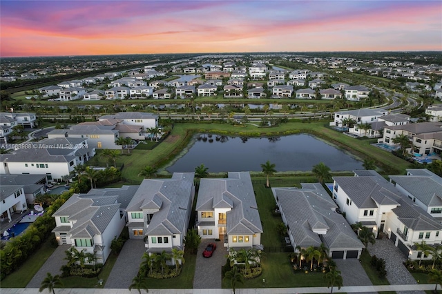 aerial view at dusk featuring a water view