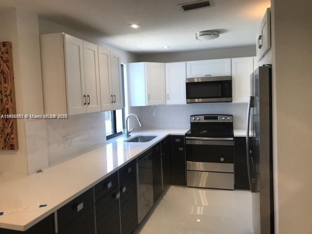 kitchen with backsplash, white cabinetry, sink, and stainless steel appliances