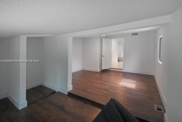 spare room with visible vents, dark wood finished floors, a textured ceiling, and baseboards