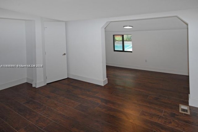 unfurnished room with baseboards, visible vents, and dark wood-type flooring