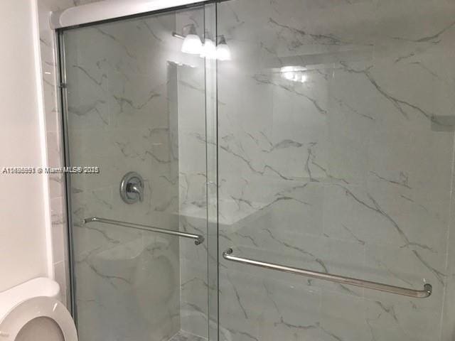 bathroom featuring a marble finish shower