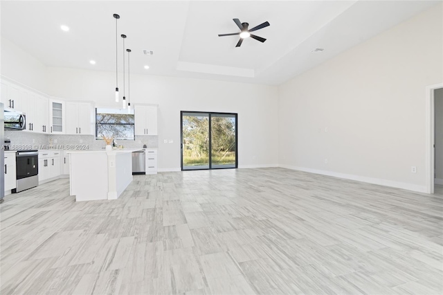 kitchen with white cabinetry, appliances with stainless steel finishes, decorative light fixtures, decorative backsplash, and a center island