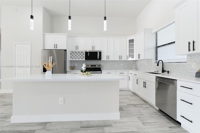 kitchen featuring white cabinets, sink, a kitchen island, appliances with stainless steel finishes, and decorative light fixtures