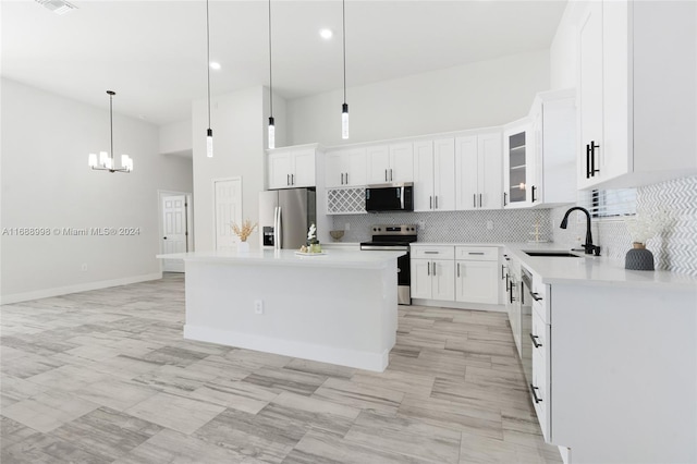 kitchen featuring stainless steel appliances, a center island, white cabinets, hanging light fixtures, and sink