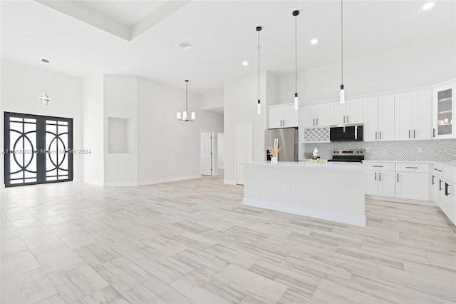 kitchen with pendant lighting, appliances with stainless steel finishes, white cabinets, and a center island