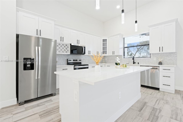 kitchen with a kitchen island, appliances with stainless steel finishes, hanging light fixtures, sink, and white cabinets