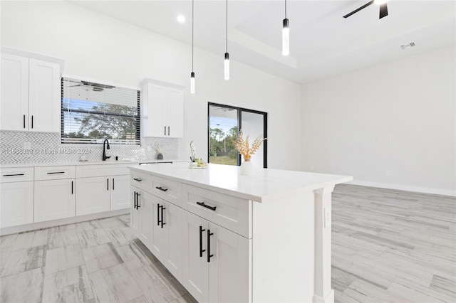 kitchen with a kitchen island, white cabinetry, hanging light fixtures, decorative backsplash, and sink