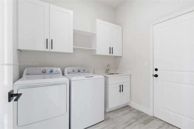 clothes washing area with separate washer and dryer, cabinets, and sink