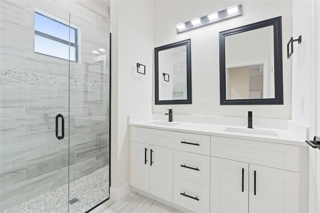 bathroom featuring a shower with shower door and vanity