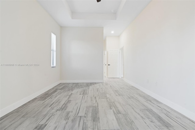 unfurnished room with light wood-type flooring and a raised ceiling