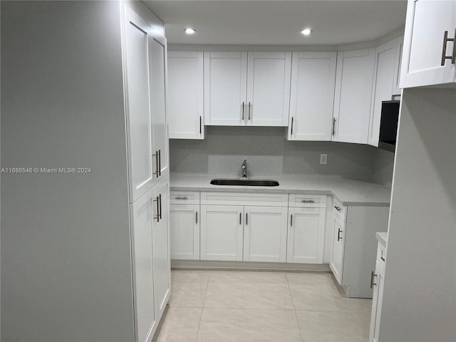 kitchen with backsplash, white cabinetry, sink, and light tile patterned floors