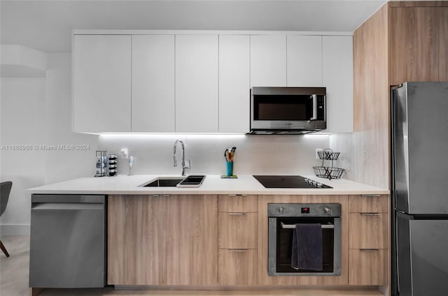 kitchen with tasteful backsplash, appliances with stainless steel finishes, sink, and white cabinets