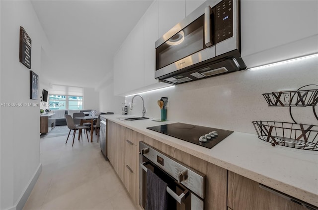 kitchen with white cabinets, appliances with stainless steel finishes, sink, and backsplash