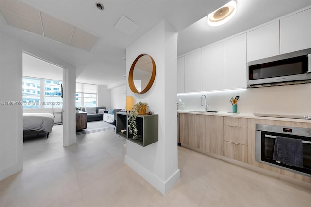 kitchen featuring white cabinets, stainless steel appliances, light brown cabinets, and sink