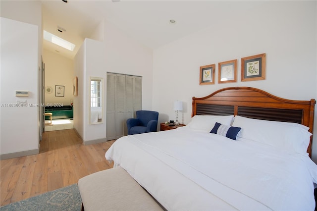 bedroom featuring high vaulted ceiling, a closet, and light hardwood / wood-style flooring