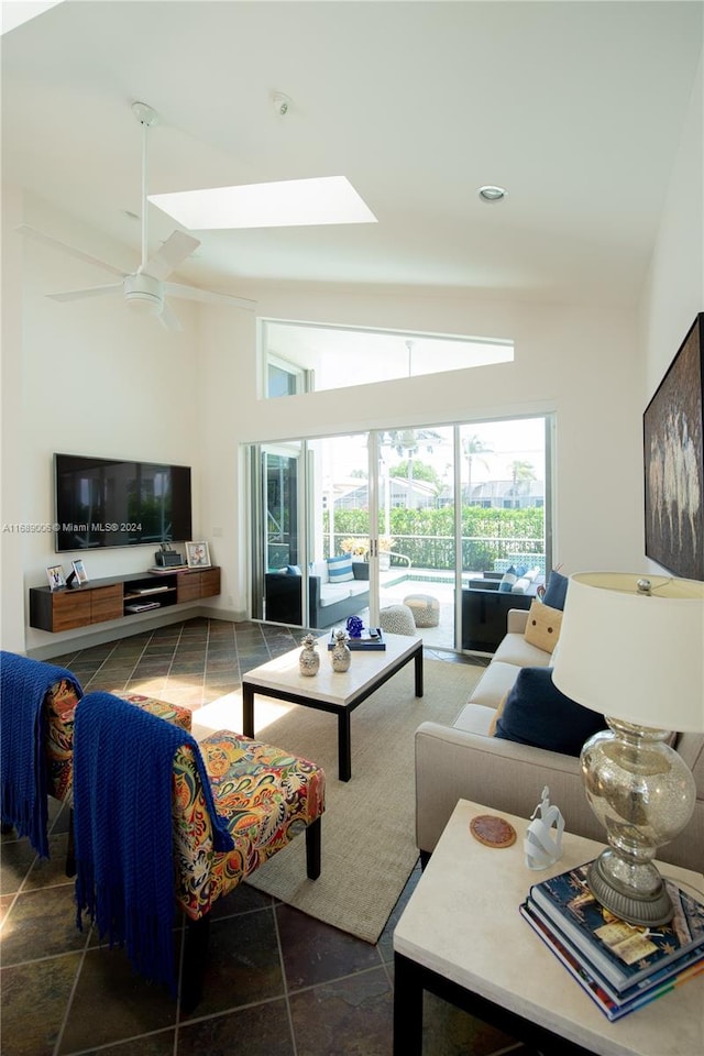 living room with ceiling fan and vaulted ceiling with skylight