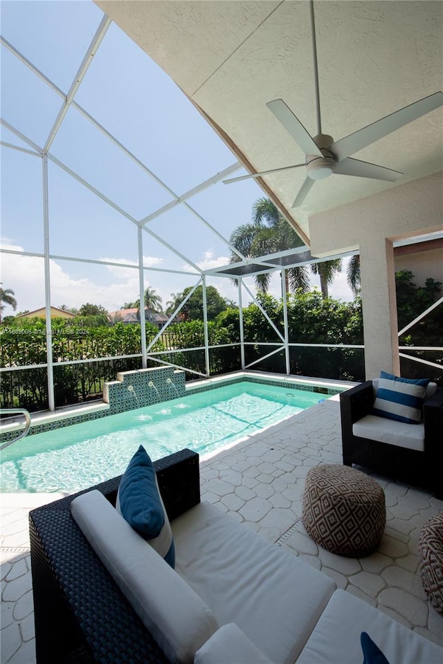 view of pool featuring a patio, outdoor lounge area, glass enclosure, and pool water feature