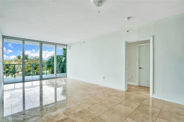 tiled empty room featuring a wall of windows