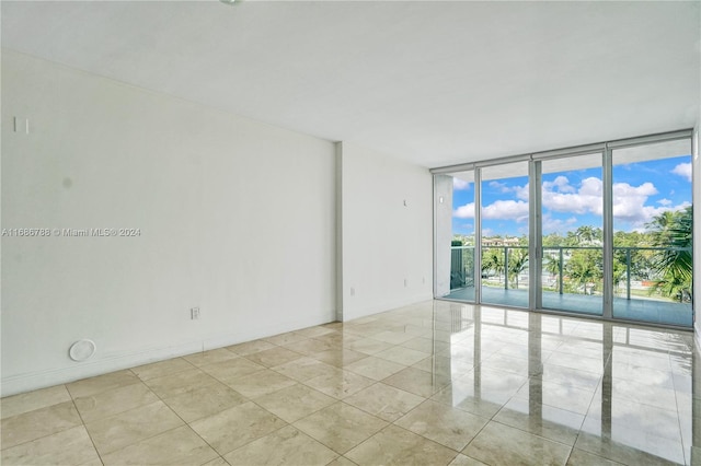 empty room featuring a wall of windows and light tile patterned floors