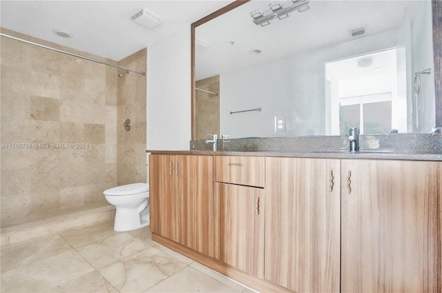 bathroom with toilet, vanity, and tiled shower