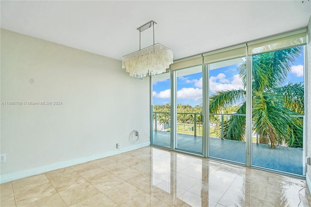 spare room featuring expansive windows and a notable chandelier