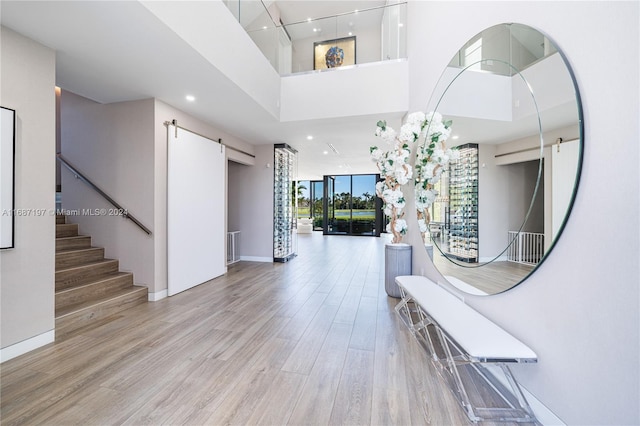 foyer entrance featuring a towering ceiling, a barn door, and light hardwood / wood-style floors