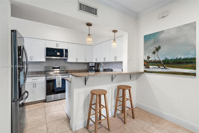 kitchen with white cabinetry, kitchen peninsula, appliances with stainless steel finishes, and decorative light fixtures