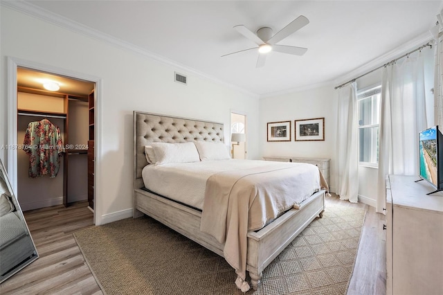 bedroom featuring light hardwood / wood-style floors, ceiling fan, crown molding, a walk in closet, and a closet