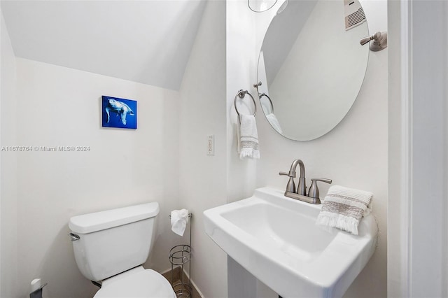 bathroom with sink, toilet, and lofted ceiling