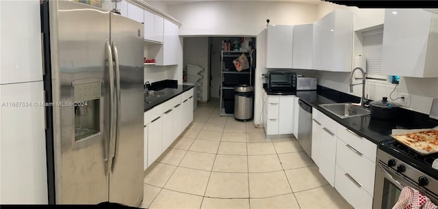 kitchen featuring light tile patterned floors, stainless steel appliances, white cabinetry, and sink