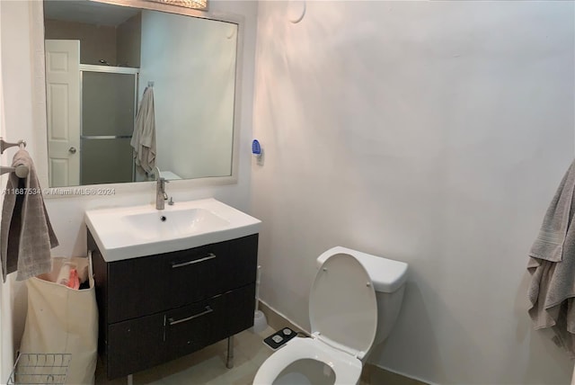 bathroom featuring vanity, toilet, and a shower with door