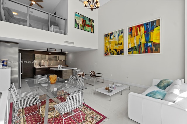 living room featuring a towering ceiling and ceiling fan with notable chandelier