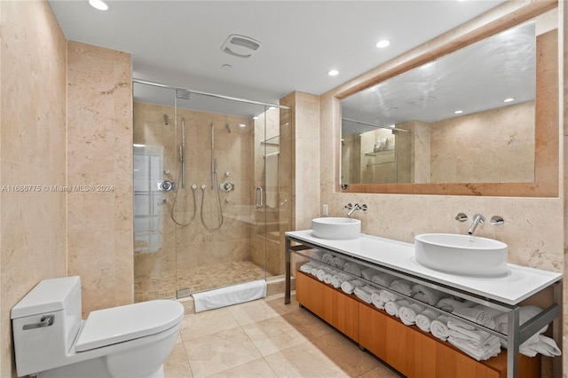 bathroom featuring tile patterned floors, toilet, a shower with door, tile walls, and vanity