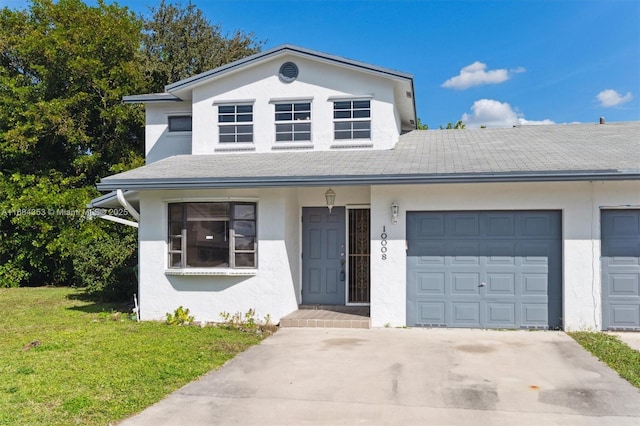 view of front of house featuring a garage, a shingled roof, concrete driveway, stucco siding, and a front yard