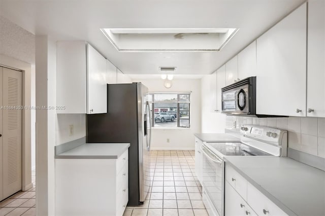 kitchen featuring tasteful backsplash, black microwave, light tile patterned flooring, white cabinets, and white electric stove