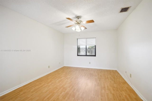 unfurnished room featuring visible vents, baseboards, light wood-style floors, and a textured ceiling