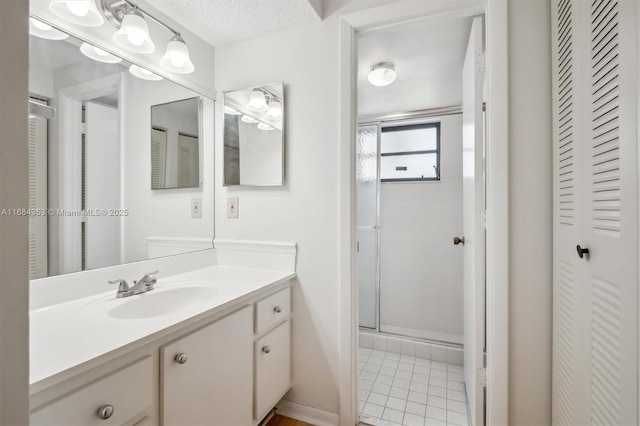 full bath featuring tile patterned floors, a textured ceiling, a closet, a shower stall, and vanity