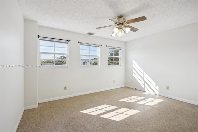 empty room featuring visible vents, baseboards, a textured ceiling, and a ceiling fan