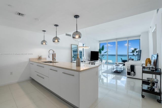 kitchen with light tile patterned flooring, pendant lighting, white cabinetry, sink, and floor to ceiling windows