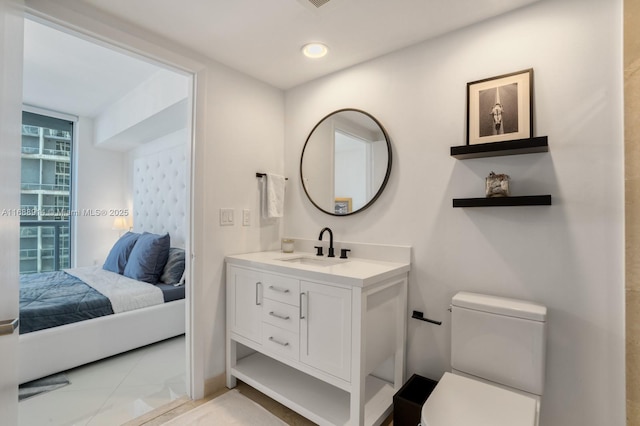 bathroom with a wall of windows, vanity, toilet, and tile patterned flooring