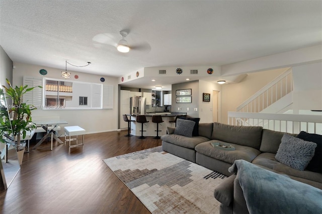 living room with a textured ceiling, dark hardwood / wood-style flooring, and ceiling fan