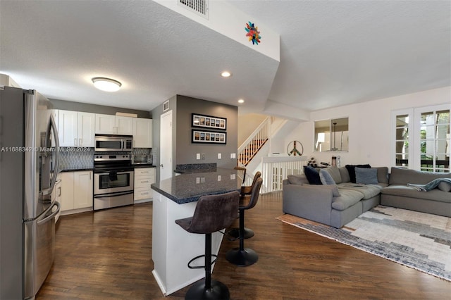 kitchen featuring stainless steel appliances, white cabinets, a breakfast bar, and dark hardwood / wood-style flooring