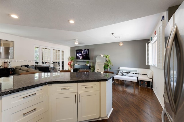 kitchen with white cabinetry, dark hardwood / wood-style flooring, a textured ceiling, and stainless steel refrigerator