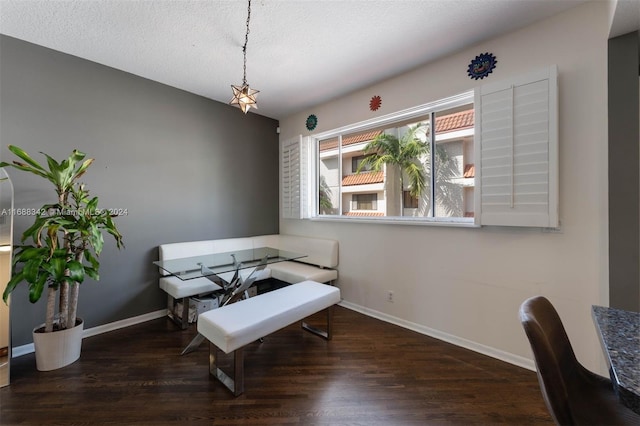 dining space featuring dark wood-type flooring and a textured ceiling