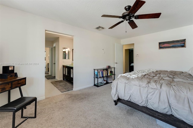 bedroom with connected bathroom, a textured ceiling, light carpet, and ceiling fan