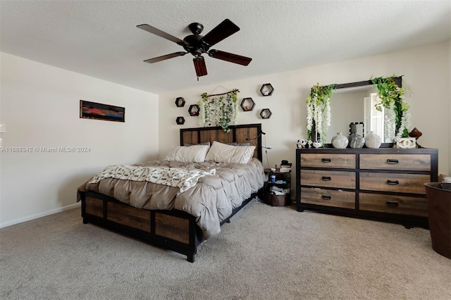 carpeted bedroom featuring ceiling fan and a textured ceiling