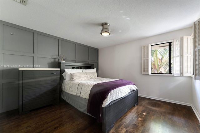 bedroom with ceiling fan, a textured ceiling, and dark hardwood / wood-style floors