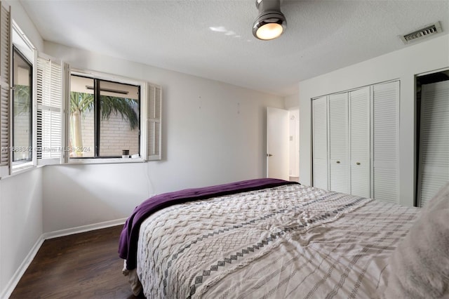 bedroom with a closet, a textured ceiling, and dark hardwood / wood-style floors